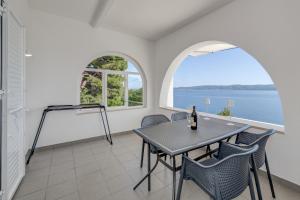 a dining room with a table and chairs and two windows at DeLuxe Seaview Apartment KENNEDY I in Mimice