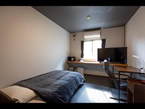 a bedroom with a bed and a desk and a television at Kiso Mikawaya in Kiso