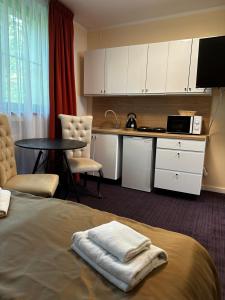 a room with a bed and a table and a kitchen at Apartamenty Giżycko in Giżycko