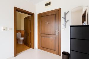 a bathroom with a wooden door and a toilet at Helios Seaview Apartment in Sveti Vlas +20 photos