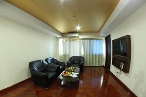 a living room with black leather furniture and a flat screen tv at Hotel Yangon in Yangon