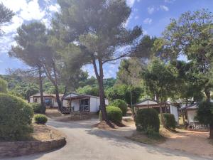 a row of cottages with trees on a dirt road at Camping Le Parc des Chênes in La Croix-Valmer +10 photos