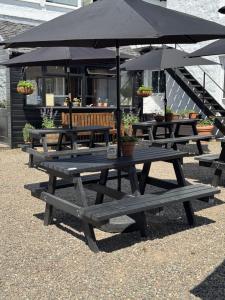 a group of picnic tables with an umbrella at The Bellachroy Hotel in Dervaig