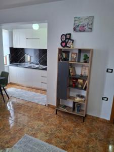 a living room with a kitchen and a book shelf at Aurora's Apartment Shkoder in Shkodër