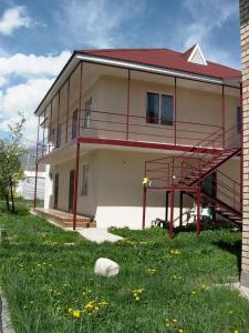 Casa con balcón rojo y césped en Meerim Murok, en Bosteri
