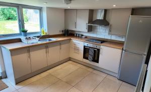 a kitchen with white cabinets and a sink and a refrigerator at Zest Homes 87a Bridge Street in Leominster
