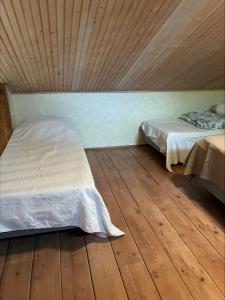 two beds in a room with wooden floors at Karhurinne Koli in Hattusaari