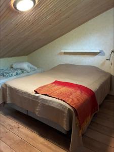 a bedroom with a bed with a red blanket on it at Karhurinne Koli in Hattusaari