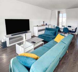 ein Wohnzimmer mit einem blauen Sofa und einem Fernseher in der Unterkunft Appartement lumineux avec terrasse et parking in Chessy