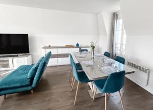 ein Esszimmer mit einem Tisch und blauen Stühlen in der Unterkunft Appartement lumineux avec terrasse et parking in Chessy + 26 Fotos