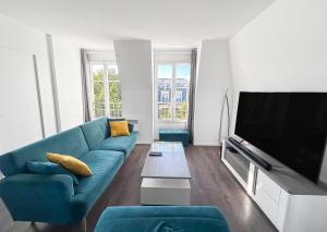 ein Wohnzimmer mit einem blauen Sofa und einem Flachbild-TV in der Unterkunft Appartement lumineux avec terrasse et parking in Chessy