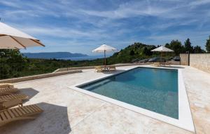 - une piscine avec 2 chaises longues et des parasols dans l'établissement Villa Mikic by Villas Guide, à Slivno Ravno