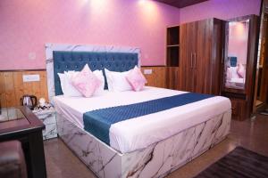 1 dormitorio con 1 cama grande y paredes de color rosa en Drift Wood Homestay, en Kūfrī