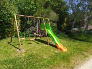two children playing on a swing set in a yard at Grande maison bretonne entre campagne et mer in Saint-Pol-de-Léon