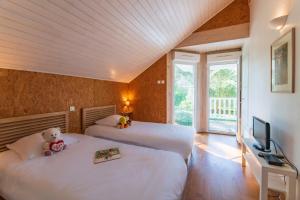 a bedroom with two beds with a tv and a teddy bear sitting on one at Résidence Lagrange Vacances Villas Eden Club in Lacanau-Océan +31 photos