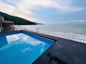 a swimming pool with a view of the ocean at Beach-Front Family Bungalow with Seaview Pool, KTV, Pool, PS5, Speaker System, BBQ & more!! in Tanjung Bungah