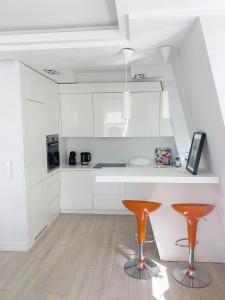 a white kitchen with orange bar stools in it at Apartament z balkonem in Sopot