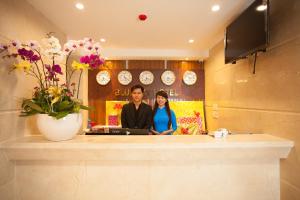 een man en vrouw die achter een toonbank staan met een laptop bij Blue Sky Phu Quoc Hotel in Phu Quoc