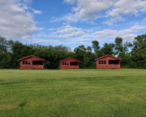 two red buildings in a field with trees at Ørsted Outdoor in Lille Ladager