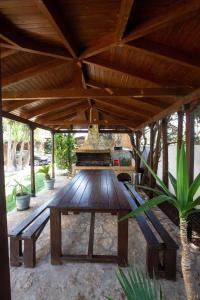 a wooden table under a wooden roof with benches at Villa Luxury Garden Kiato in Pásion