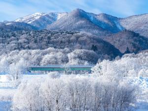 un train circulant sur un champ enneigé avec des montagnes dans l'établissement Hill House B NakaFurano Hokkaido JAPAN, à Nakafurano