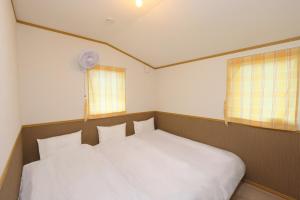 - une chambre avec un lit blanc et 2 fenêtres dans l'établissement Hill House B NakaFurano Hokkaido JAPAN, à Nakafurano