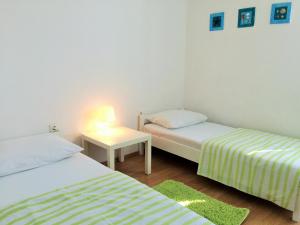 Cette chambre comprend deux lits et une table avec une lampe. dans l'établissement Apartments Parać, à Petrčane