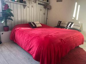 a red bed with two pillows on top of it at au Bonheur - Praloup 1600 - Au cœur de la station et au pied des pistes - La voile des neiges - parking commun privé - local ski in Pra-Loup