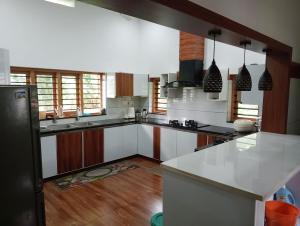 a kitchen with a white counter top and wooden floors at Izzath in Kottakkal