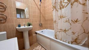 a bathroom with a sink and a tub and a shower curtain at EmmaApart Comfort 169 in Astana +2 photos