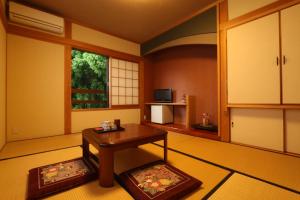 un soggiorno con tavolo e finestra di Minshuku Asogen ad Aso