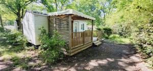 a wooden cabin with a porch in the woods at Mobil Home 4 6 pers climatisé Camping Eurolac in Aureilhan