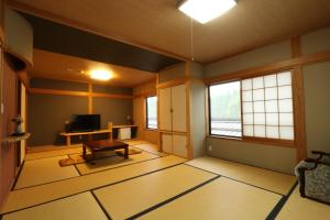 a room with a living room with a tv and windows at Minshuku Asogen in Aso