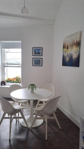 a white dining room with a white table and chairs at 1A Cathedral Place - Cathedral Townhouses Cobh in Cobh +7 photos