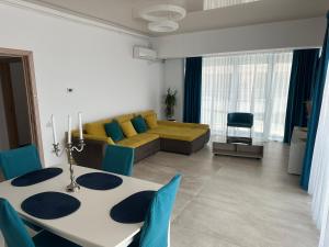 ein Wohnzimmer mit einem Tisch und einer gelben Couch in der Unterkunft Zev-S10 in Mamaia Nord – Năvodari + 8 Fotos