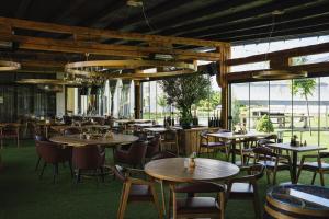 ein Restaurant mit Tischen und Stühlen und Fenstern in der Unterkunft Domeniile Martinutzi - Hotel Cardinal si Conac Rhedey in Alba Iulia