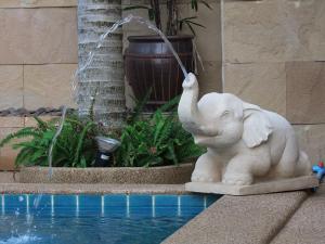a statue of an elephant drinking water from a fountain at Katanoi Resort in Kata Beach