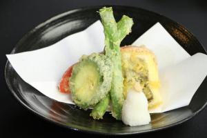 a black plate with some food on it at Minshuku Asogen in Aso