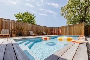 una piscina con sillas y una valla de madera en La Cabane du Naissain 5 stars, en Saint-Georges-dʼOléron