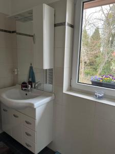 ein weißes Badezimmer mit Waschbecken und Fenster in der Unterkunft Comfy & Cozy Apartment in Neuenhagen