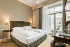 a bedroom with a large white bed and a desk at Hotel Europa Splendid in Merano
