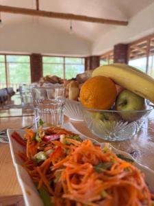 a table with a plate of food and a bowl of fruit at Eco Village Lodge in Dzhetyoguz