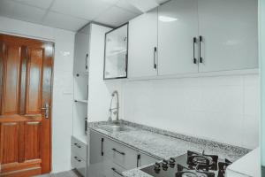 a kitchen with white cabinets and a sink at Le Parvis Résidences in Yaoundé