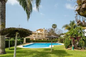 una piscina davanti a una casa con palme di Brisamar a Chiclana de la Frontera