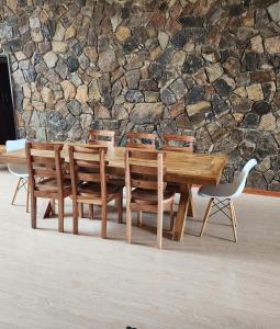 un tavolo in legno con sedie di fronte a un muro di pietra di Nyanga Home in Private Village 2033 a Nyanga