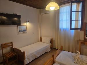 a room with two beds and a tv and a window at Zeus room 3 beds in Panagia