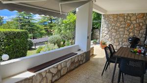a patio with a table and chairs and a stone wall at Apartments 4U in Omišalj