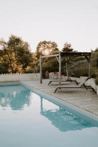 a pool with a wooden deck and a gazebo at Les Nuits du Taris in Bourdeaux