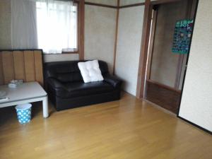- un salon avec un canapé en cuir noir et une table dans l'établissement Guesthouse Face to Face, à Fujinomiya