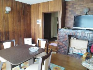 a dining room with a table and a brick fireplace at Guesthouse Face to Face in Fujinomiya